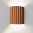 Wall-mounted light fixture with a ribbed brown design on a white wall.