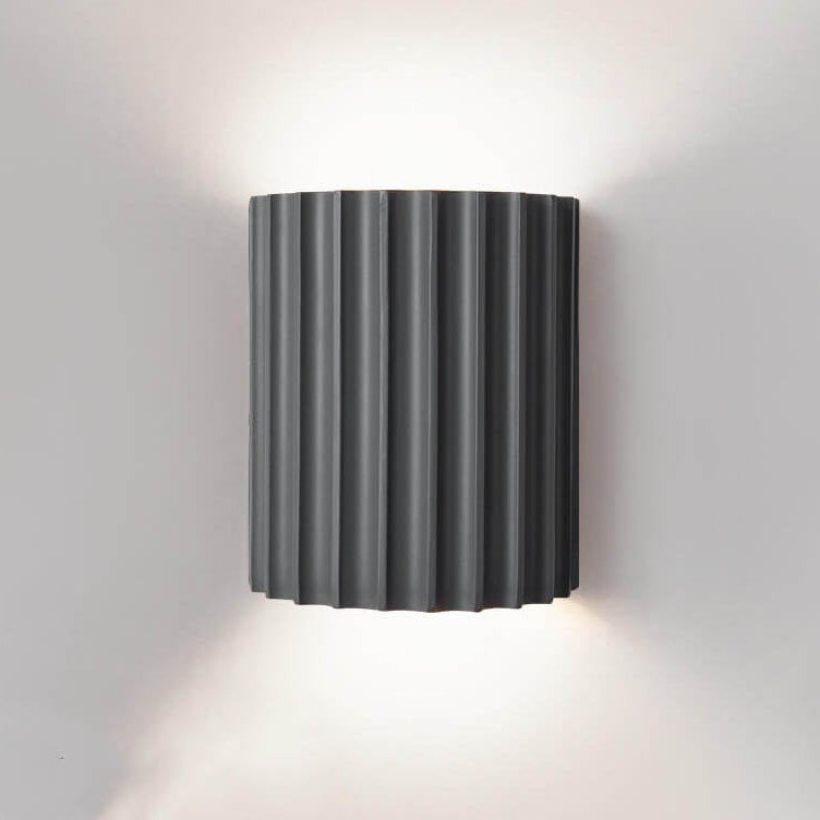 Black wall-mounted lamp with ribbed design on a gray wall