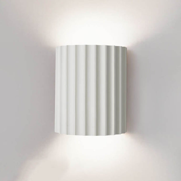 Wall-mounted lamp with striped design on a plain wall
