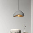 Concrete pendant light hanging above a white chair with a minimal background