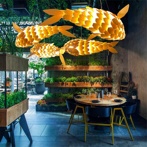 Modern restaurant interior with artistic fish-shaped pendant lights and a dining table.